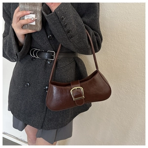 Retro dark brown crescent shoulder bag with golden metal buckle on grey blazer