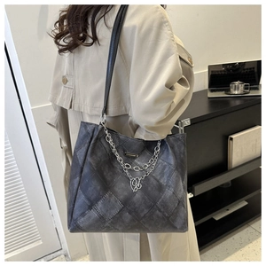 Detail of dark gray tote bag with retro diamond patchwork and silver chain decoration