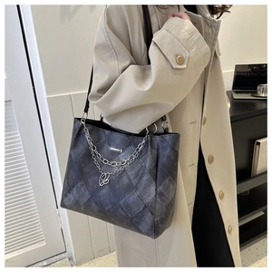 Detail of grey vintage plaid tote bag with silver chain and metal letter charm