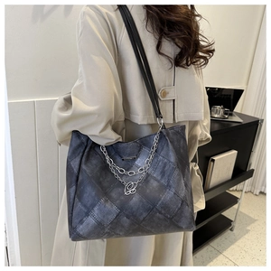 Detail of grey vintage plaid denim tote bag with silver chain and metal pendant