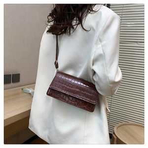 Brown crocodile pattern crossbody bag styled on a white blazer for a chic fashion look