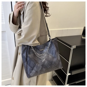Model wearing dark grey oversized tote bag with diamond lattice pattern and chain detail