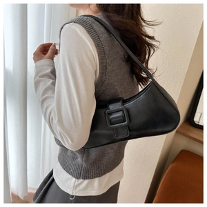Detail view of a black underarm bag featuring a large square buckle and matte leather texture