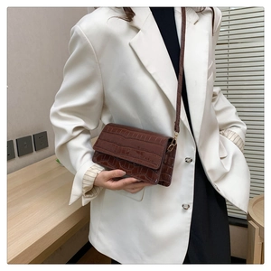 Side view of dark brown crocodile pattern crossbody bag shown on a model