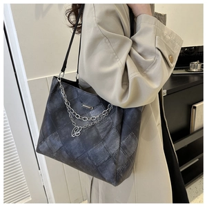 Detail view of large grey tote bag with heart charm and silver metal chain decoration