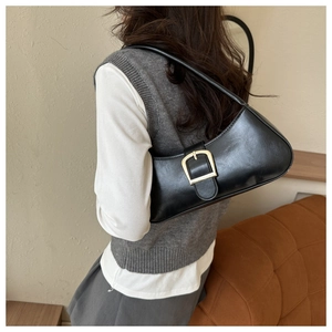 Close-up of black crescent shoulder bag with golden metal buckle on a model's shoulder