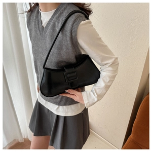 Close-up of minimalist black crescent shoulder bag with a matte finish and large buckle detail