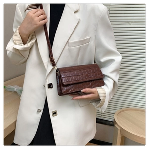 Dark brown crocodile embossed leather crossbody bag with white blazer outfit styling