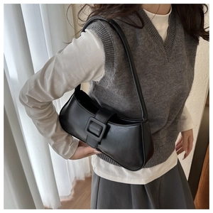 Close-up of a black matte leather underarm bag with a vintage square buckle detail