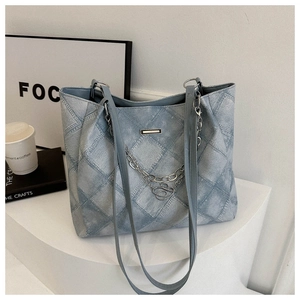 Close-up of light blue quilted denim tote bag with metallic heart chain decoration