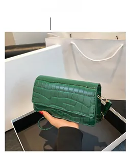 Macro detail of green crocodile-embossed leather finish on a chic crossbody flap bag