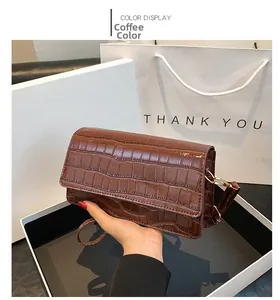 Detail view of brown crocodile texture leather bag with glossy finish and gold buckle