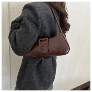 Close-up of a vintage dark brown leather baguette bag with a decorative square buckle