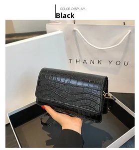 Detail of glossy black crocodile embossed mini bag with elegant gold metal hardware buckle