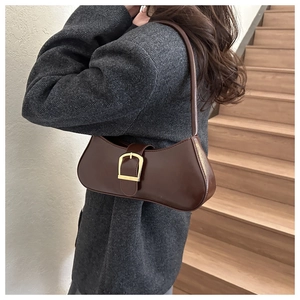 Detail of vintage brown leather underarm bag with gold metal buckle on tweed coat
