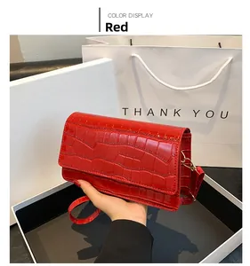 Detail of red croc-embossed small square bag with glossy faux leather and shoulder strap