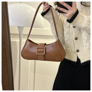 Detail of a brown matte leather underarm bag featuring a retro large square buckle design