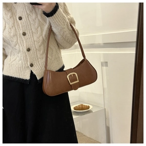 Detail of vintage brown baguette bag with gold buckle on a chic French-style background