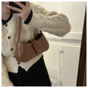 Close-up of a vintage brown leather baguette bag with a square buckle detail on the strap