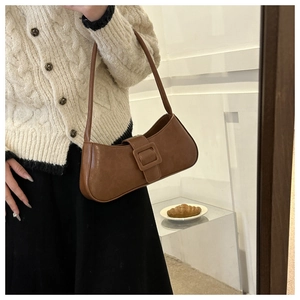 Close-up of vintage brown baguette bag featuring a decorative large square leather buckle