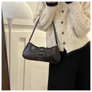 Close-up of a vintage dark brown baguette bag with buckle strap on a model shoulder