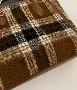 Detailed view of plaid wool tote bag showing texture and brown leather trim details
