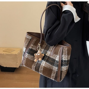 Detail view of the retro plaid woolen tote bag with leather straps and plush charm