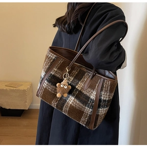 Close-up of checkered wool tote bag with leather trim and a cute teddy bear charm