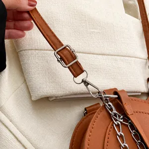 Detail of silver chain strap and adjustable buckle on a brown leather handbag