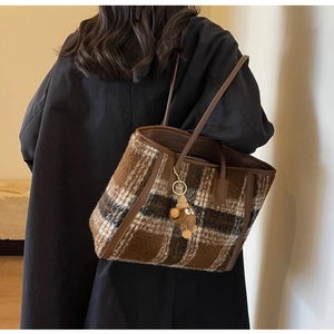 Detail of checkered wool tote bag with soft texture and cute teddy bear pendant