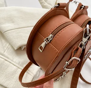 Detail of a brown round heart purse showing the silver zipper and smooth leather texture