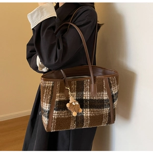 Detail of wool-like plaid tote bag featuring brown checkered pattern and bear charm