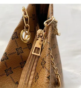Detail of smooth gold zipper closure and metal chain on vintage brown monogram tote bag