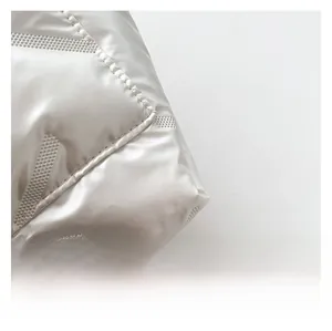 Detailed close-up of glossy white quilted fabric with precise diamond stitching