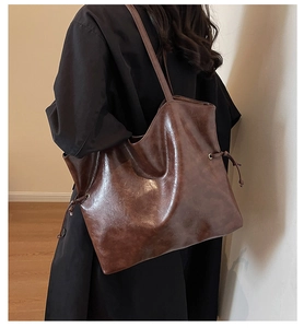 Détail du sac cabas marron foncé avec cordons latéraux et texture lisse effet ciré