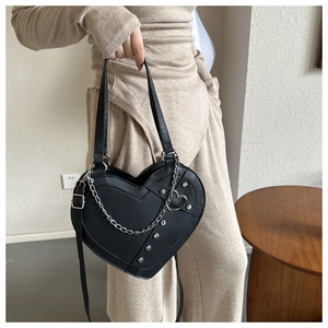 Detail of black heart-shaped PU leather bag with silver metal chains and rivets
