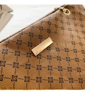 Close-up of brown litchi leather texture with rhombic floral patterns and gold hardware