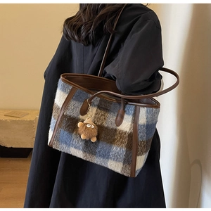 Detail of wool tote bag with blue and brown check pattern and faux fur pompom charm