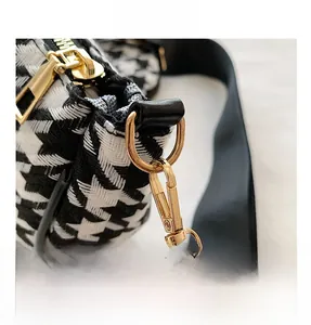 Close-up of golden hardware and houndstooth pattern fabric on a women crossbody bag
