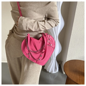 Detail showing pink heart-shaped leather bag with silver chain, rivets and cross charm