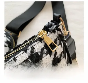 Detail of black and white houndstooth fabric with premium gold hardware and wide strap