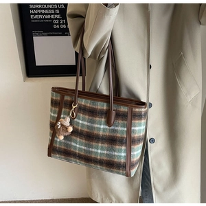 Detail of checkered woolen tote bag with leather trim and brown teddy bear charm