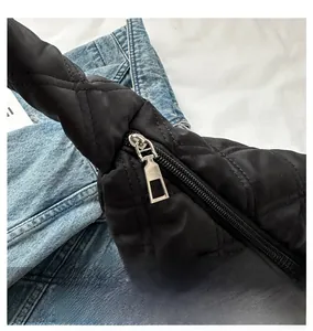 Détail d'un sac bandoulière noir matelassé avec une fermeture éclair en métal argenté