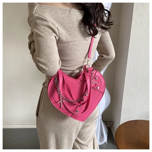 Detail of rose pink heart-shaped crossbody bag with silver chains and cross pendant