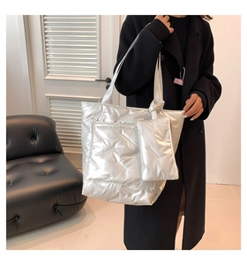 Detail of silver quilted puffer tote bag set with matching zippered pouch on shoulder