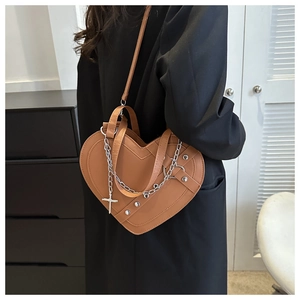 Detail view of heart-shaped brown bag with metal chains and rivets on a blazer