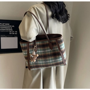Detail of plaid wool tote bag with leather trim and brown plush charm accessory