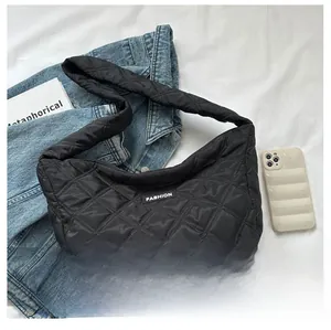 Détail d'un sac cabas noir matelassé avec étiquette de mode sur fond de tissu blanc