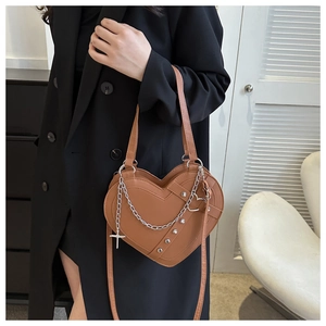 Detail of heart-shaped crossbody bag with silver chains, studs and a cross pendant