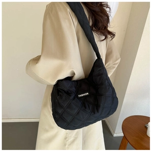 Détail du grand sac cabas matelassé noir avec une étiquette logo de mode cousue dessus